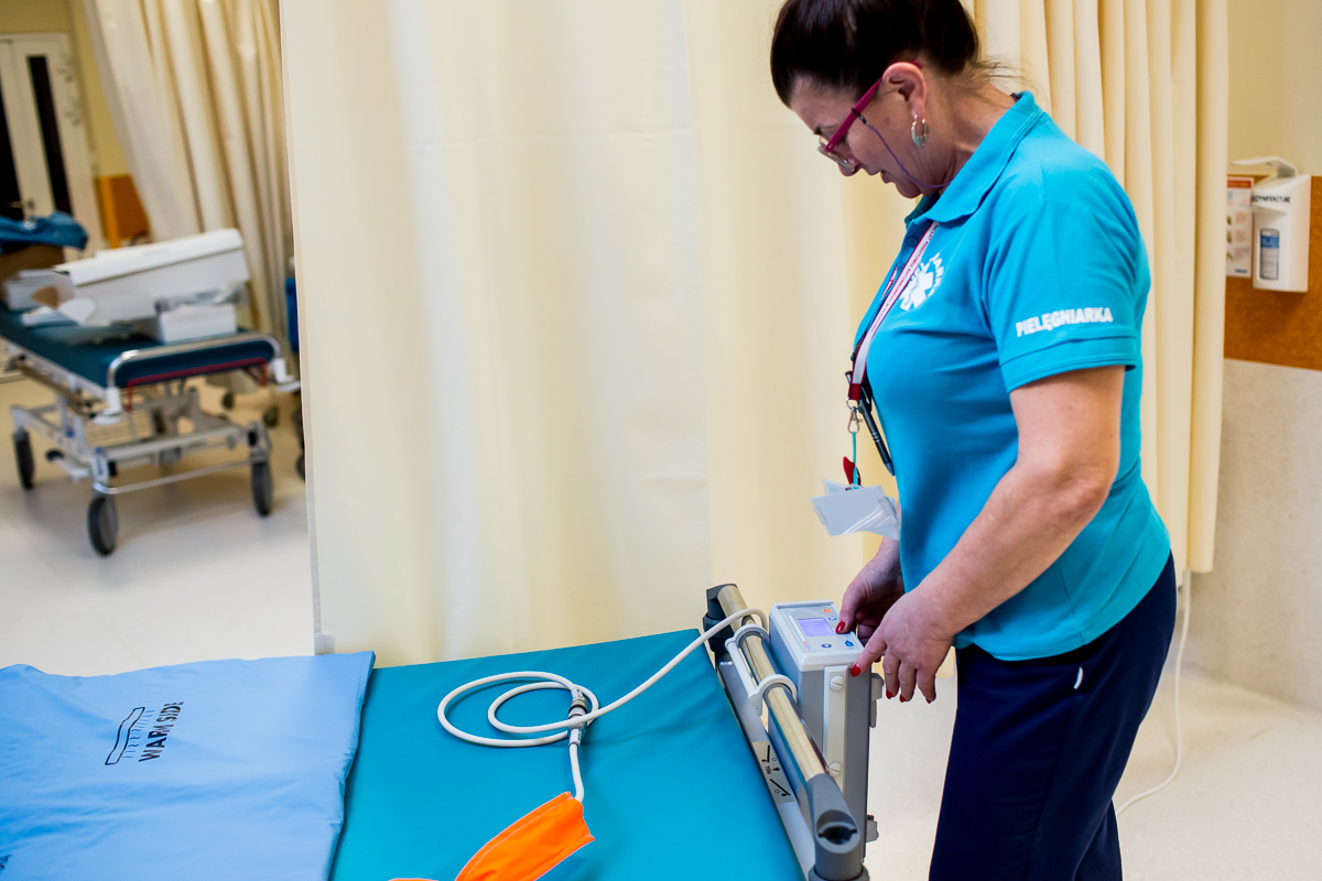 Na zdjęciu osoba przygotowująca ł&oacute;żko na oprzyjęcie pacjenta